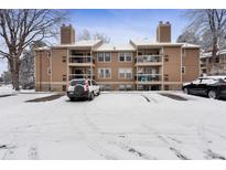 Exterior of a brown condo building with balconies and snow-covered parking lot at 10950 W Florida Ave # 303, Lakewood, CO 80232