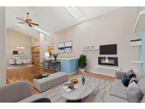 Bright living room with a fireplace, fan, skylight and open access to the kitchen at 4195 W 111Th Cir, Westminster, CO 80031