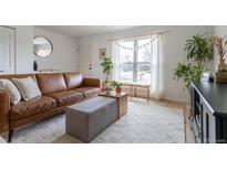 Bright living room featuring a comfortable brown leather sofa, plants, and large windows at 4653 S Yank St, Morrison, CO 80465