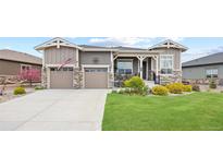 Charming home featuring a well-manicured lawn, stone accents, a two-car garage, and inviting front porch at 22580 E Eads Cir, Aurora, CO 80016