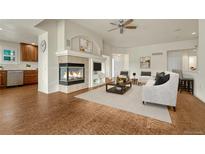 Open-concept living room with fireplace and view into the adjacent kitchen at 22380 E Heritage Pkwy, Aurora, CO 80016