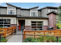 Modern two-story townhome with gray siding, brick accents, and a wooden fence at 10155 Morrison Rd, Lakewood, CO 80227