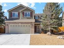 Charming two-story home featuring a well-maintained lawn, brick accents, and an attached two-car garage at 7453 S Norfolk St, Aurora, CO 80016