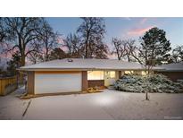 Charming ranch-style home with brick and siding exterior, snow-covered yard, and attached two-car garage at 2842 S Newport St, Denver, CO 80224