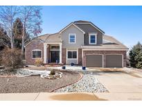 Charming two-story home featuring a brick facade, tile roof, manicured yard, and an attached two-car garage at 2451 S Fenton Dr, Lakewood, CO 80227