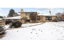 Charming two-story brick home with a manicured front yard covered in snow at 3860 Dudley St, Wheat Ridge, CO 80033