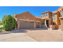 Stunning two-story stone house featuring a three-car garage and an expansive driveway at 9351 Viaggio Way, Highlands Ranch, CO 80126
