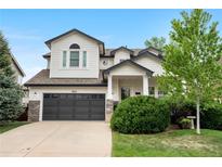 Charming two-story home with manicured lawn, mature trees, and dark grey garage door at 9631 S Dover Way, Littleton, CO 80127