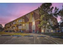 Three-story apartment building featuring brick accents, individual balconies, and reserved parking spaces at 10211 Ura Ln # 304, Thornton, CO 80260