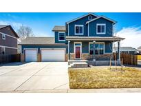 Charming two-story home with a two-car garage and well-maintained front yard and blue siding at 2091 Basil St, Strasburg, CO 80136