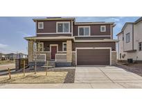 Two-story home with brown siding, brick accents, and a two-car garage on a sunny day at 798 Sawdust Dr, Brighton, CO 80601