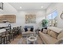 Open living area with modern sofas, coffee table, and large windows at 3553 W 63Rd Ave, Denver, CO 80221