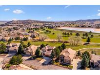 Stunning aerial view of homes nestled on a golf course community with a picturesque lake and mountain backdrop at 16611 Red Cliff Cir, Morrison, CO 80465
