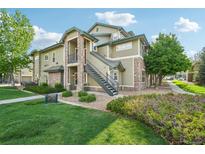 A light-green, two-story condo featuring stone accents and stairs to the second-story entrance at 5800 Tower Rd # 1201, Denver, CO 80249