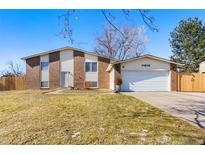 Charming two-story home with a brick and vinyl exterior, a well-manicured lawn, and an attached two-car garage at 15876 E Flora Pl, Aurora, CO 80013