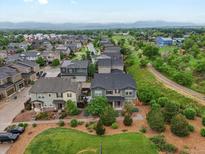 Expansive aerial view of a neighborhood showcasing well-maintained homes and lush green spaces, with mountains in the distance at 14823 W 70Th Dr # A, Arvada, CO 80007