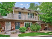 Charming two-story townhome featuring a brick facade, balcony, green door and a well-maintained front yard at 6880 E Appleton Cir, Centennial, CO 80112