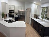 Modern kitchen featuring stainless steel appliances, white cabinets, and white marble countertops at 1896 S Marshall Cir, Lakewood, CO 80232