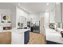 Bright kitchen featuring white cabinets, stainless steel appliances, a large island, and a cozy fireplace nearby at 1896 S Marshall Cir, Lakewood, CO 80232