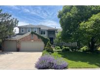 Charming two-story home with a well-manicured lawn, lush greenery, and brick accents at 5272 W Capri Pl, Littleton, CO 80123