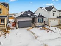 Two-story house with gray siding and stone accents, a two-car garage, and a partially snow-covered front yard at 3361 N Buchanan Way, Aurora, CO 80019