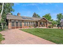 Inviting home featuring a brick and stucco facade, covered porch, and well-maintained front lawn at 6223 W Flora Pl, Denver, CO 80227