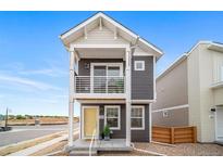Charming two-story home with a balcony and a welcoming yellow front door at 13029 E 103Rd Pl, Commerce City, CO 80022