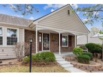 Charming brick home featuring a cozy front porch, manicured landscaping, and inviting curb appeal at 9954 W Progress Pl, Littleton, CO 80123