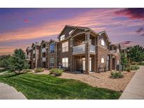 Beautiful multi-story condo building with stone accents, private balconies, and well-manicured lawn at 7440 S Blackhawk St # 14-208, Englewood, CO 80112