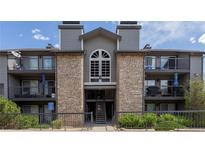 Apartment building featuring stone accents, gray siding, and balconies with outdoor seating at 2575 S Syracuse Way # M206, Denver, CO 80231