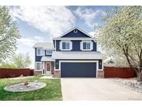 Charming two-story home with a well-maintained lawn, garden bed and a blue exterior and white trim at 21742 E Lehigh Pl, Aurora, CO 80018