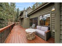 Inviting deck with a comfortable couch and a stone fire pit table perfect for outdoor gatherings and relaxation at 3065 Piney Ridge Rd, Evergreen, CO 80439