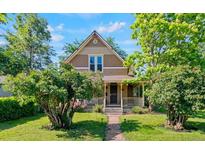Charming two-story home with a covered porch and landscaped front yard surrounded by lush greenery and a stone walkway at 3039 W 22Nd Ave, Denver, CO 80211