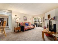 Cozy living room featuring a fireplace, a plush sofa, and a sliding glass door leading to the outside at 14806 E 2Nd Ave # 104G, Aurora, CO 80011
