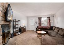 Cozy living room featuring a fireplace, carpet, and an inviting brown sectional couch at 14272 E Hawaii Cir # B, Aurora, CO 80012