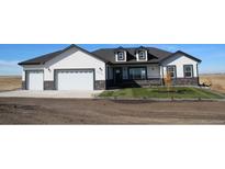 Charming home featuring a manicured lawn, stone accents, and an attached two-car garage at 56315 E 74Th Ave, Strasburg, CO 80136