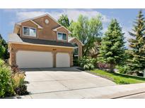 Tan two-story home with a two-car garage and well-manicured lawn and mature trees in a suburban neighborhood at 531 Saber Creek Dr, Monument, CO 80132