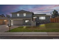 Charming home with stone facade, lush lawn, and inviting front entrance at dusk at 6844 W 69Th Pl, Arvada, CO 80003