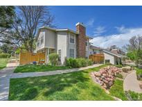 Charming exterior view of townhome with a brick chimney, green lawn, and well-maintained landscaping at 7077 S Knolls Way, Centennial, CO 80122