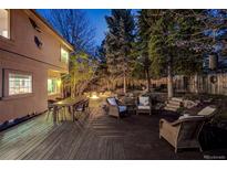 A dark wooden deck featuring comfortable wicker seating surrounds a charming fire pit perfect for evening relaxation at 2464 Ginny Way, Lafayette, CO 80026