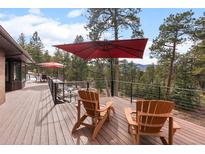 Spacious deck boasts outdoor seating with an umbrella and mountain views at 7845 Armadillo Trl, Evergreen, CO 80439