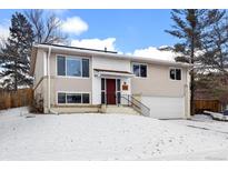 Charming two-story home features a red front door, attached garage, and manicured landscaping at 12843 W Jewell Cir, Lakewood, CO 80228