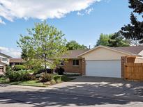 Charming single-Gathering home featuring a brick facade, lush landscaping, and an attached two-car garage at 12420 W Atlantic Ave, Lakewood, CO 80228