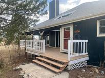 Inviting home entrance with a covered porch, painted railings, and a classic red door at 44626 Lariat Trl, Elizabeth, CO 80107