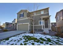 Two-story home with an attached garage and a well-manicured lawn and snowy landscaping at 1908 Homestead Dr, Fort Lupton, CO 80621