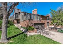 Charming two-story home with brick and gray siding, attached garage and mature trees at 6969 W Yale Ave # 81, Denver, CO 80227