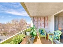 Inviting balcony with wicker chairs, plants, and a scenic view of surrounding greenery at 1090 N Lafayette St # 504, Denver, CO 80218