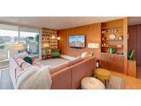Eclectic living room featuring a cozy pink sofa, wood paneling and bright floral curtains at 1090 N Lafayette St # 504, Denver, CO 80218