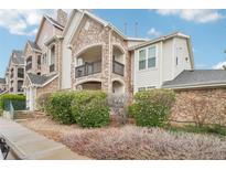 Charming condo featuring stone accents, a private balcony, and mature landscaping at 19019 E Warren Dr # H104, Aurora, CO 80013
