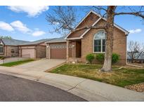 Charming brick home with a well-manicured lawn, a two-car garage and a concrete driveway at 4927 Greenwich Way, Highlands Ranch, CO 80130
